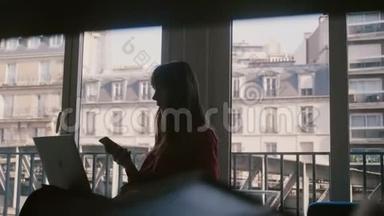 漂亮专注的年轻女商人使用笔记本电脑，在巴黎的公寓窗口打电话，<strong>火车经过</strong>。